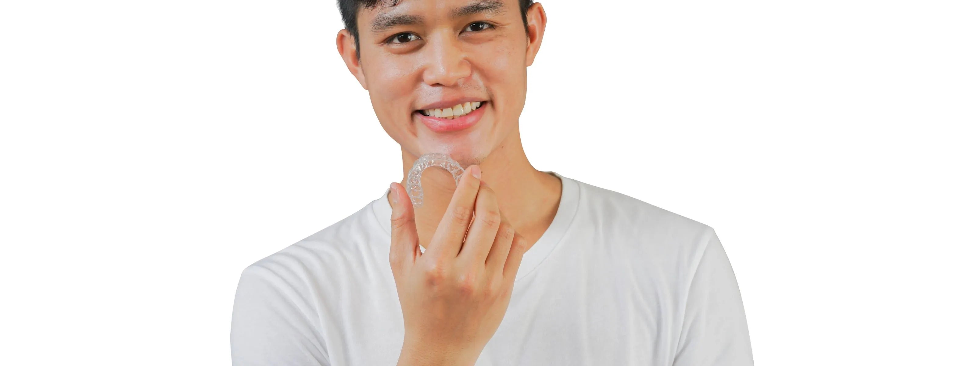 young teenger boy holding an invisalign tray looking at the camera, white background