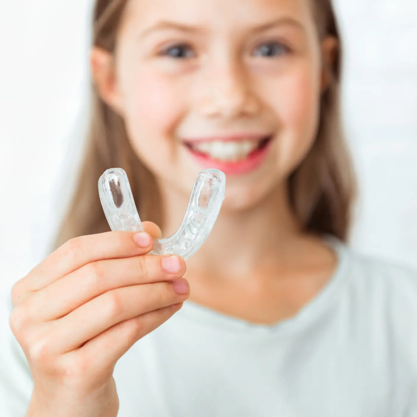 child holding an invisalign tray in her hand