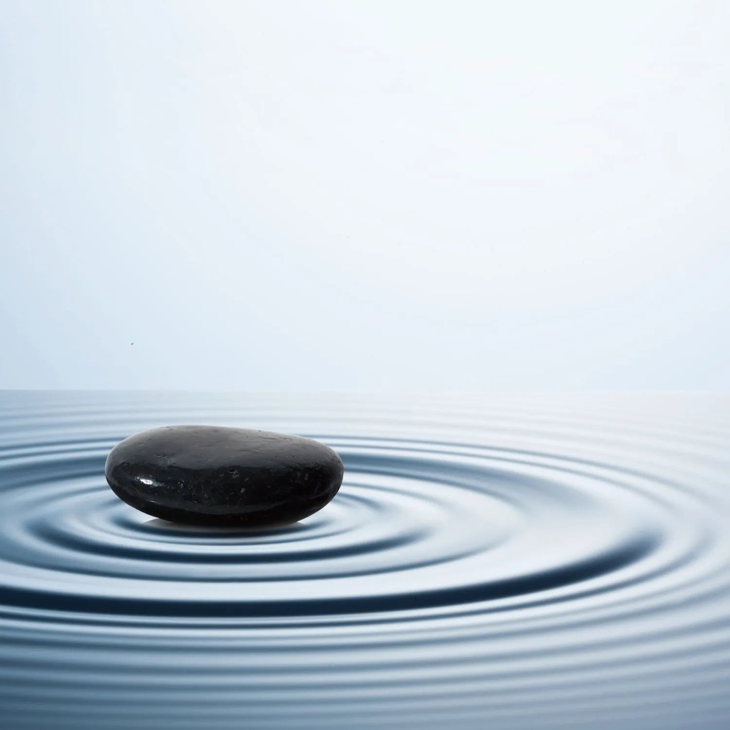 zen black stone on top of ripples of water