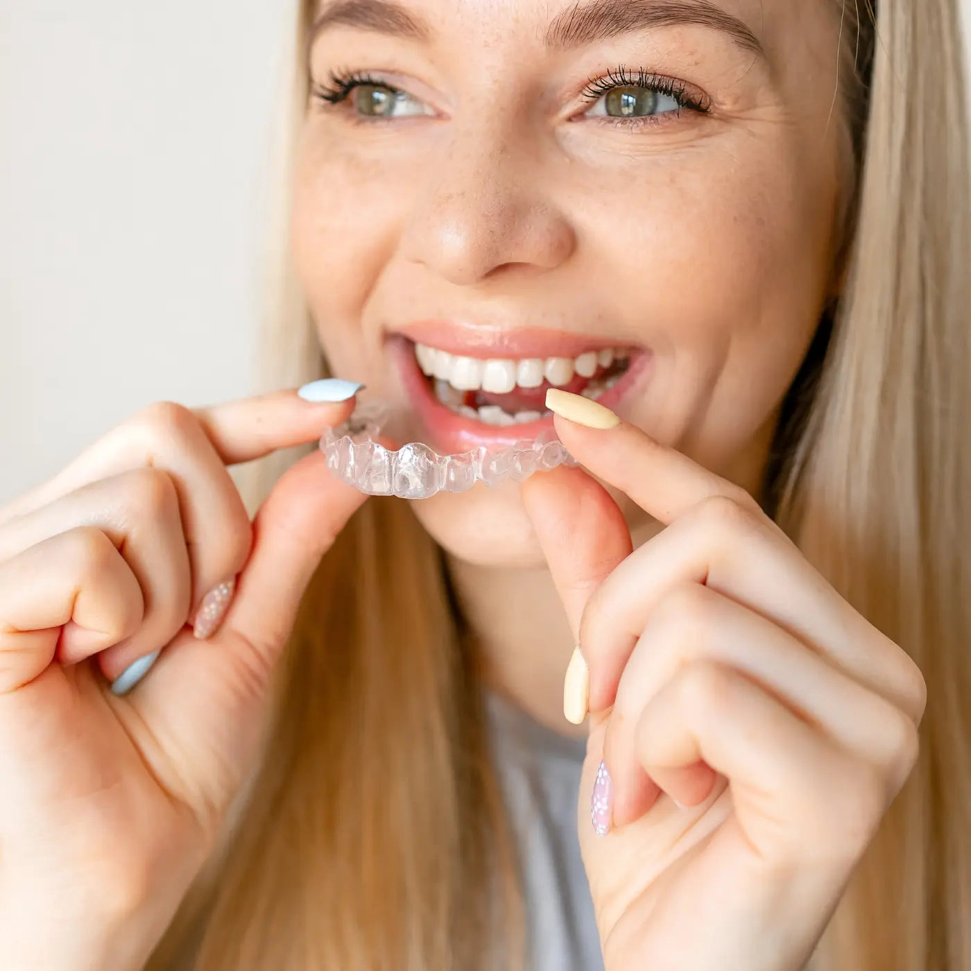 woman holding her invisalign tray readiy to fit it on her teeth