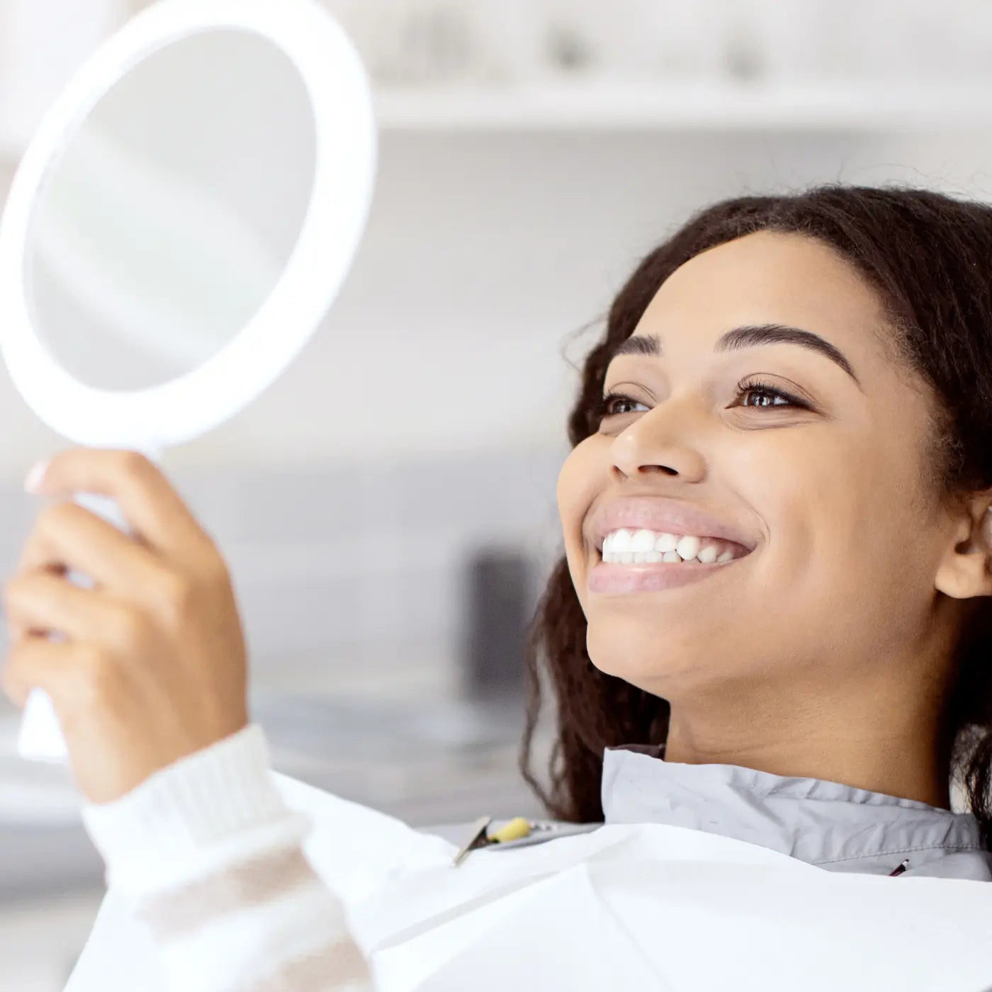 woman looking at her smile in a mirror