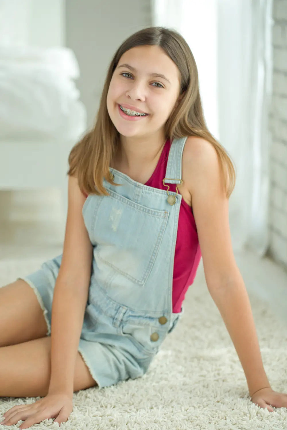young girl sitting on the floor smiling with fixed braces