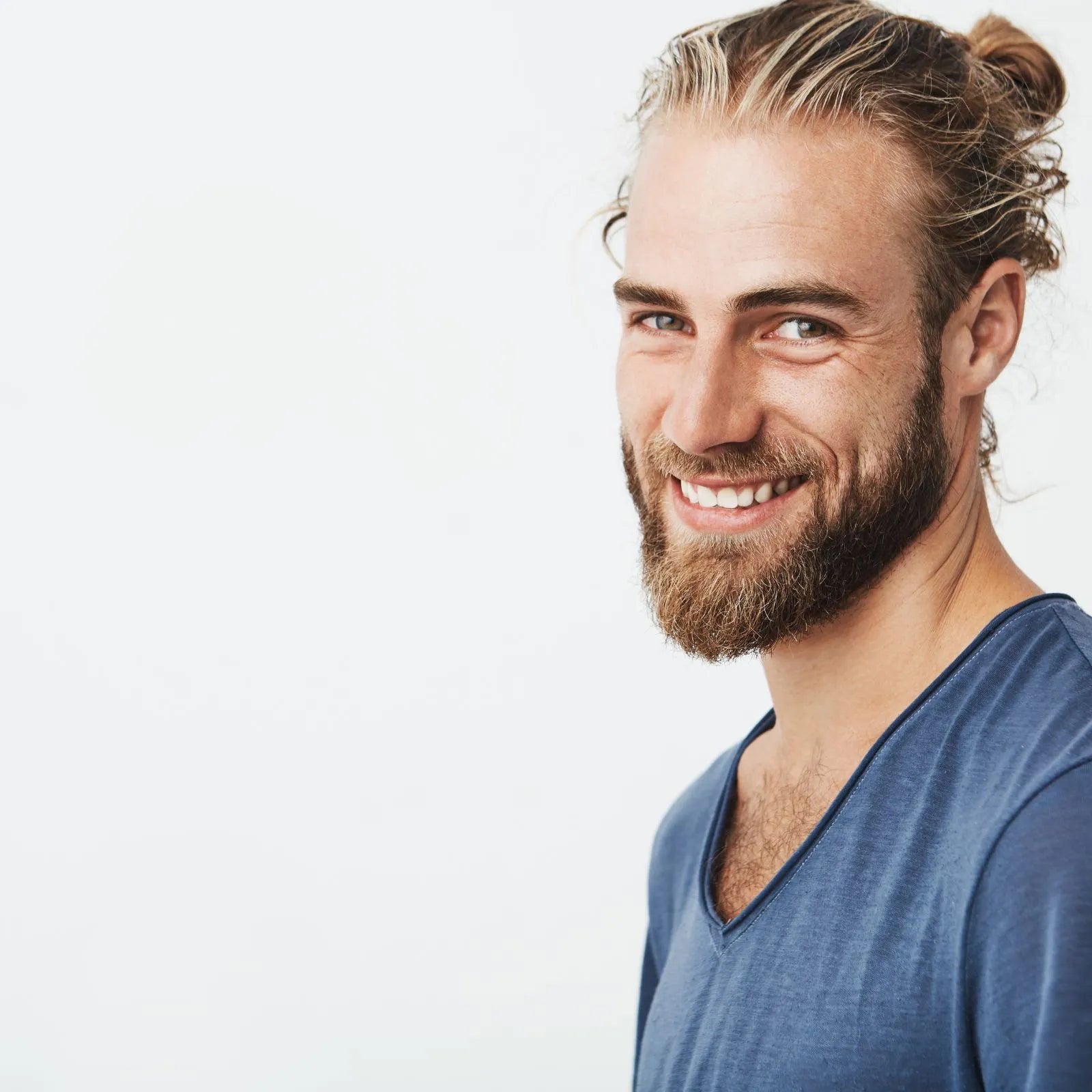man with a pony tail smiling to the camera