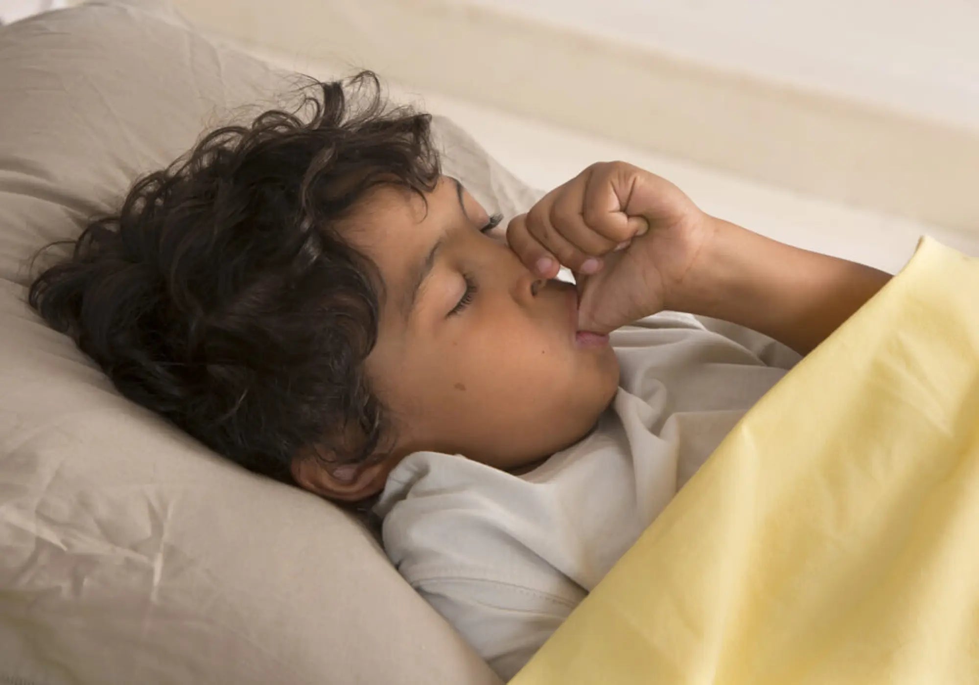 child in bed sucking his thmb