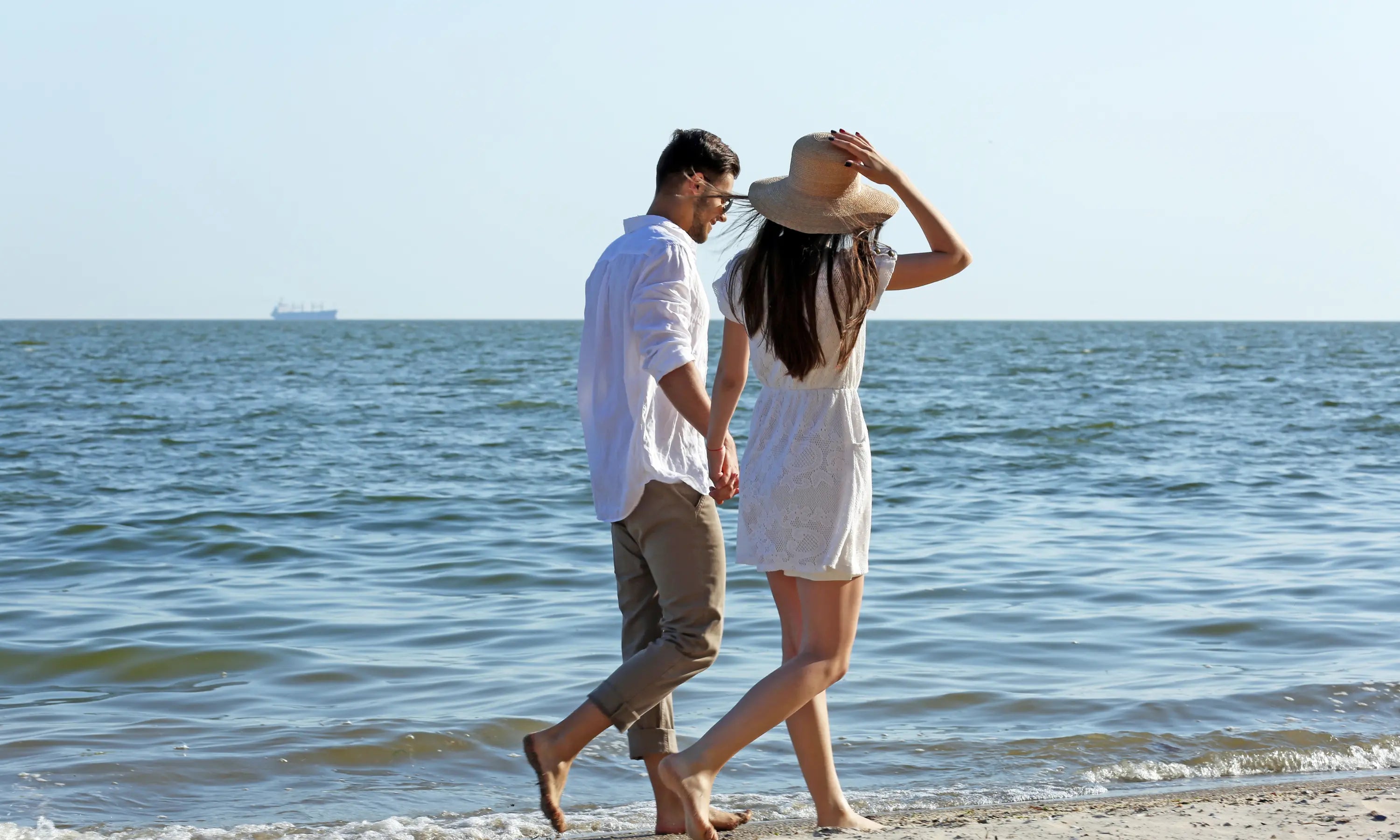 couple hilding hands walking along the beach