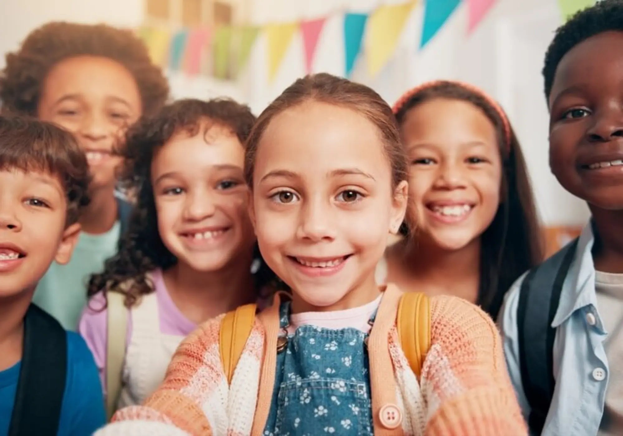 Group of children smiling with colorful flags in the background