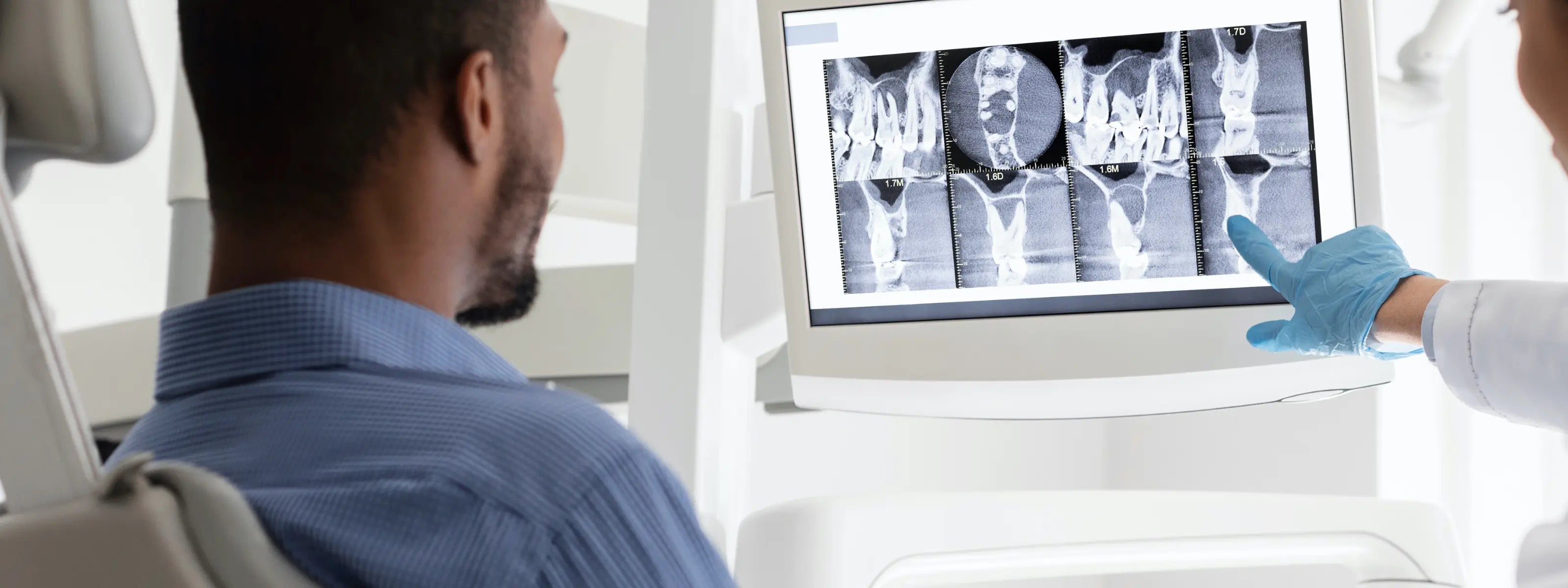 patient on dental chair looking at an x-ray with his orthodontic treatment